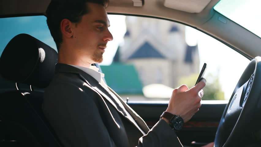 Sat drive. Man in a car dialing Phone. Man in car holding Flag.